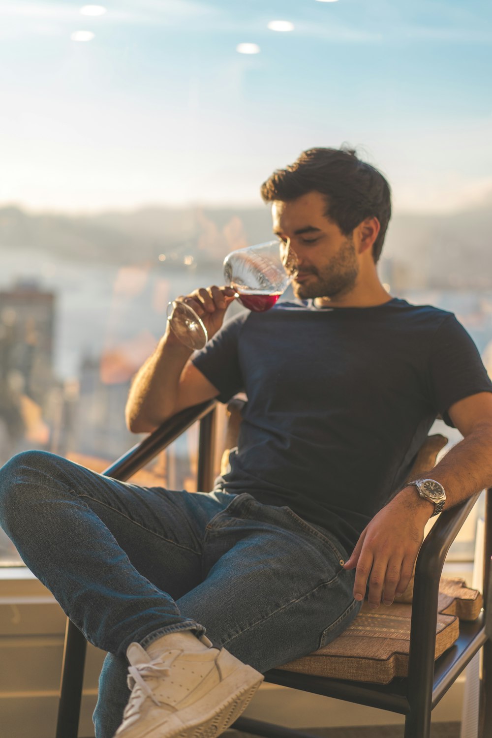 homem na camiseta preta do pescoço da tripulação e jeans azul sentado na cadeira