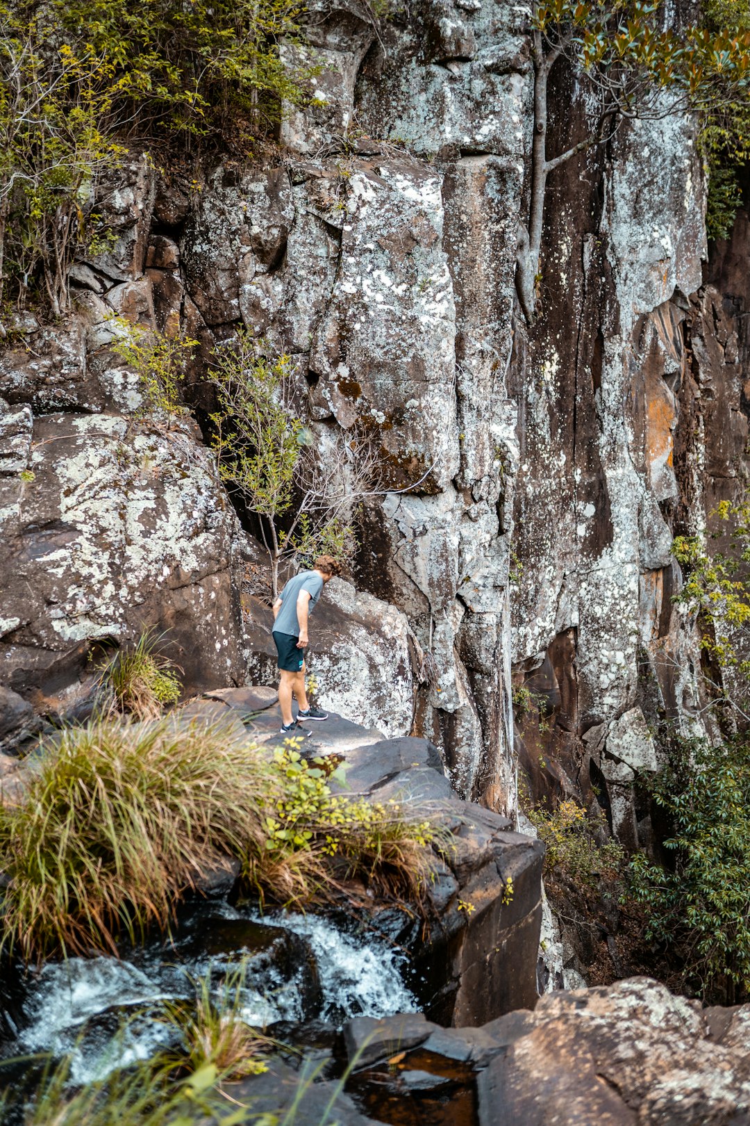 woman in white t-shirt climbing on brown rock