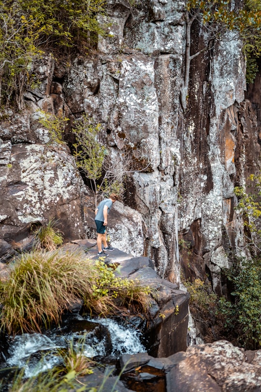 woman in white t-shirt climbing on brown rock in Gold Coast Australia