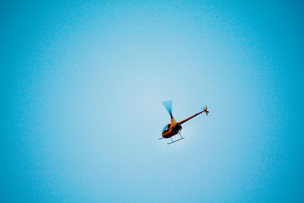 orange and white helicopter flying in the sky
