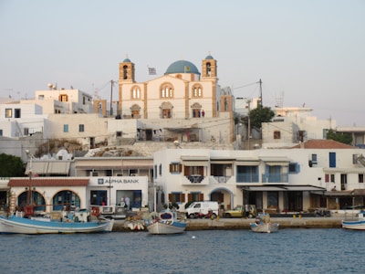 white and blue boat on body of water near white concrete building during daytime