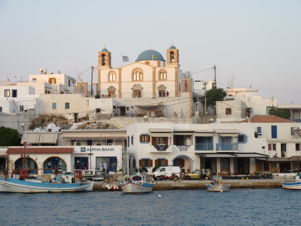 white and blue boat on body of water near white concrete building during daytime