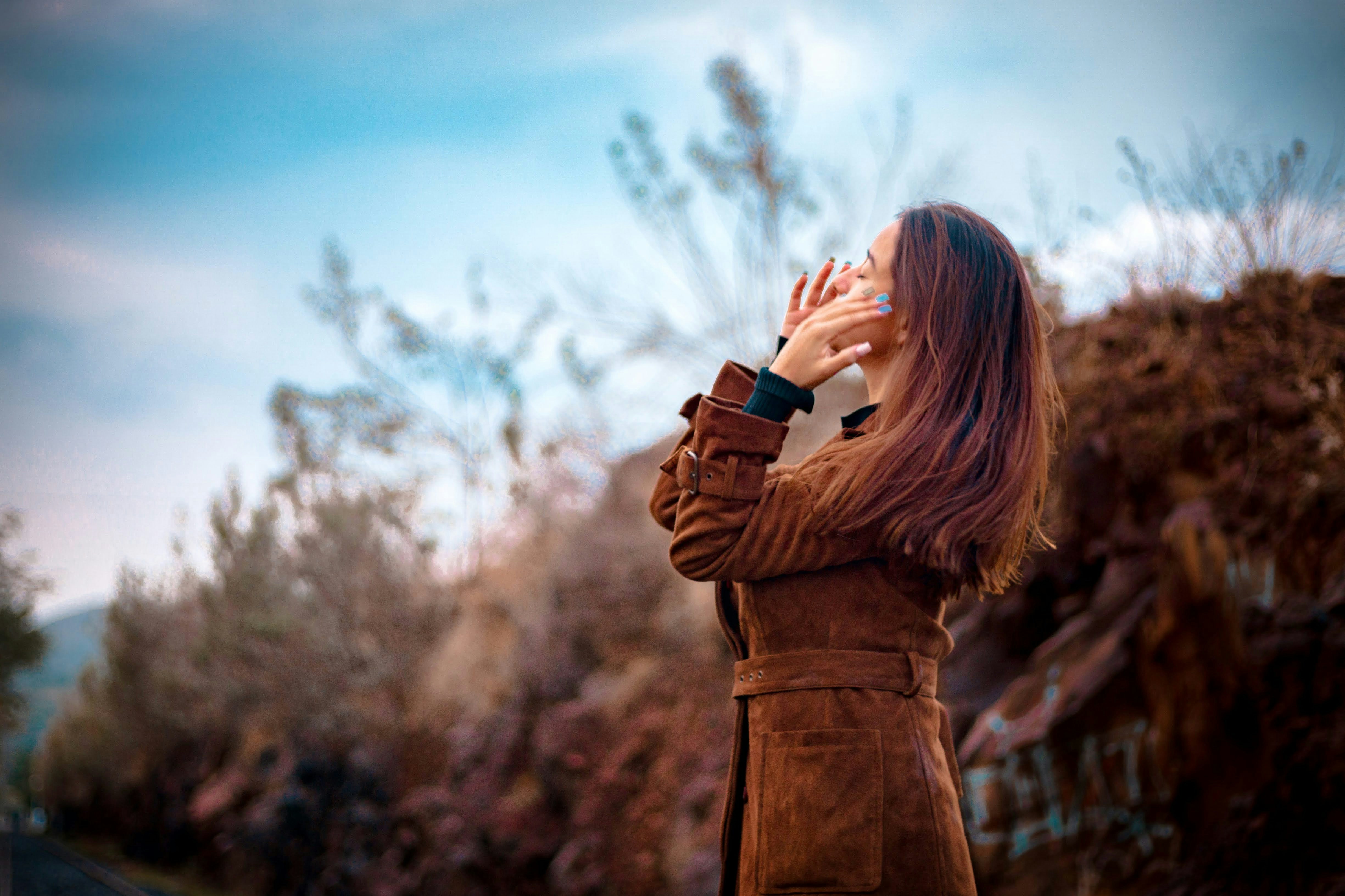 woman in brown coat holding black camera