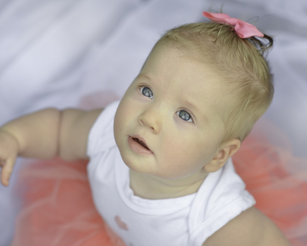 baby in white shirt lying on bed