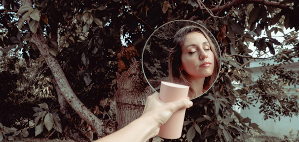 Close-up of a serene woman gently touching her clear, healthy skin outdoors.