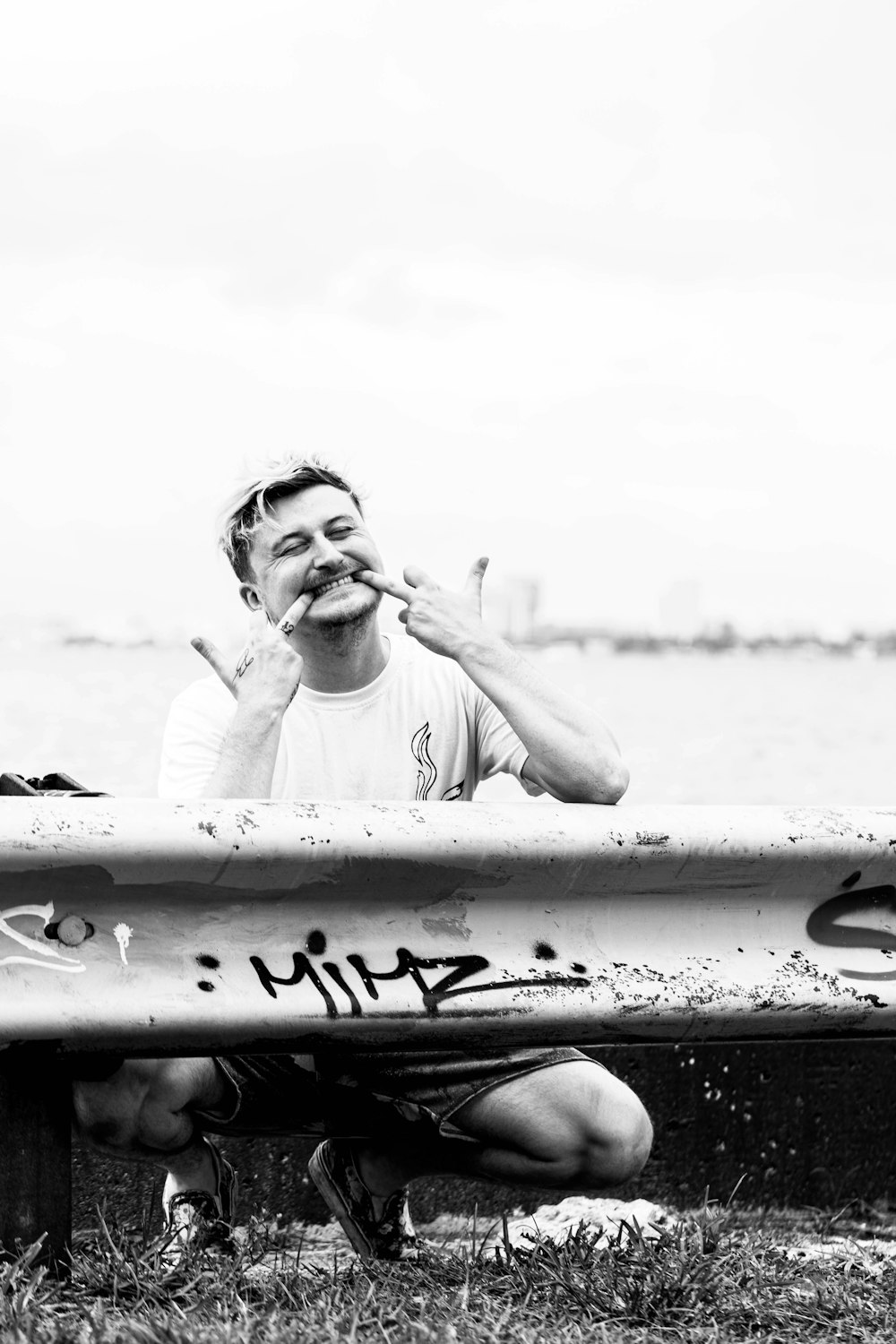 man in white crew neck t-shirt smoking cigarette in grayscale photography