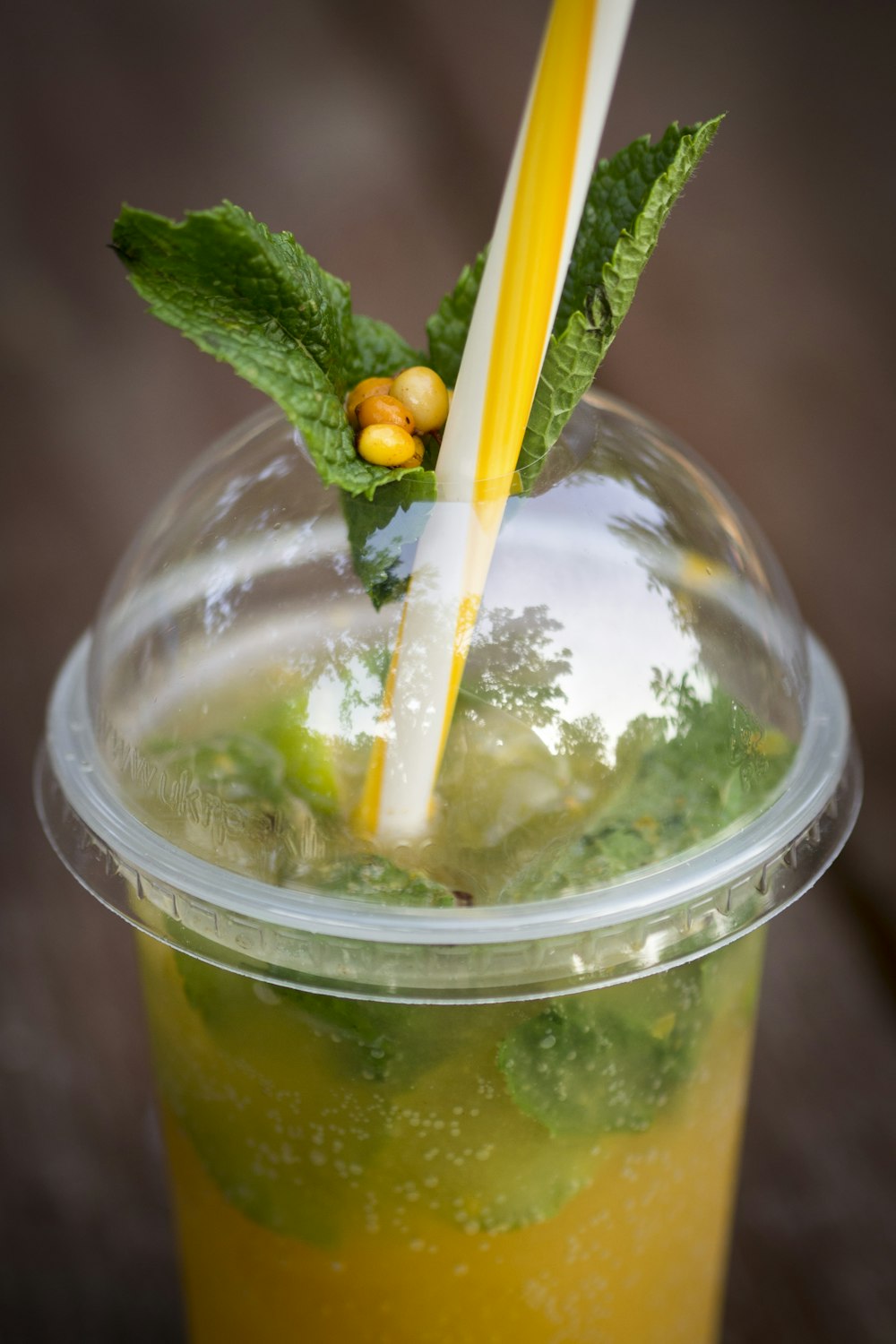 clear plastic cup with yellow liquid and green leaf