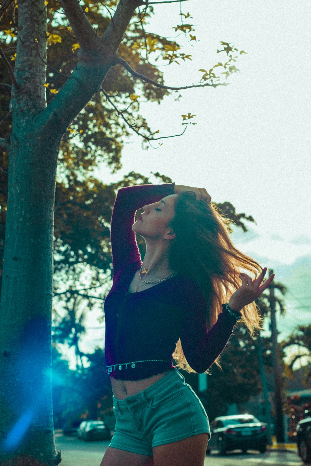 woman in black long sleeve shirt and blue denim jeans standing beside brown tree during daytime