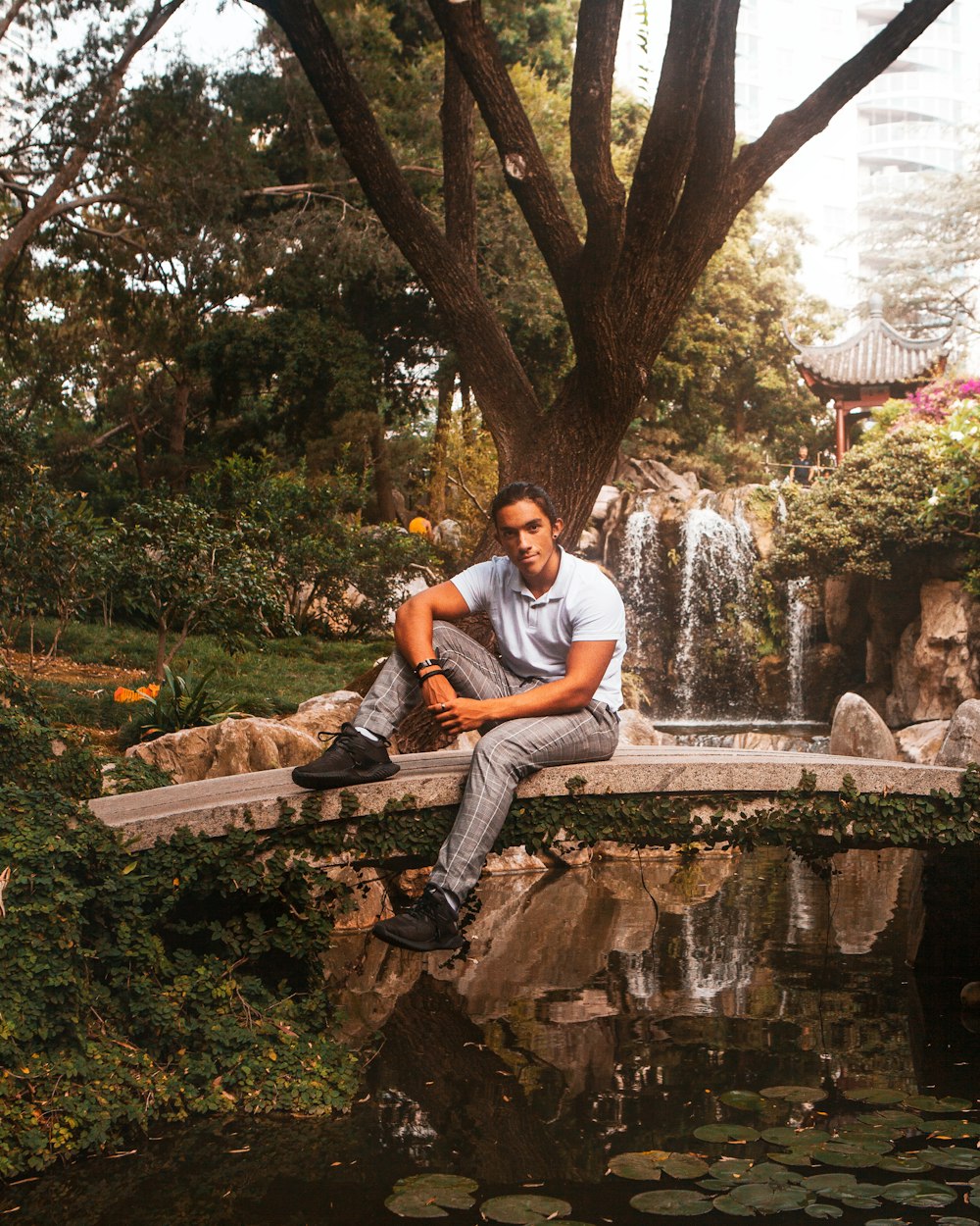 man in white crew neck t-shirt and blue denim jeans sitting on concrete bench during