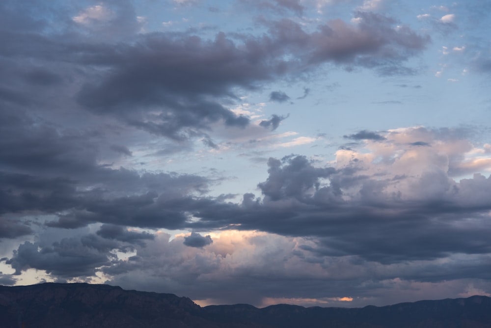 silhouette of mountain under cloudy sky during sunset