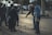 A group of elderly people are gathered in a park, playing a game of pétanque. They are focused on the arrangement of metal balls scattered on the sandy ground. One person is pointing towards the balls as others observe intently, demonstrating the social and engaging nature of the game.