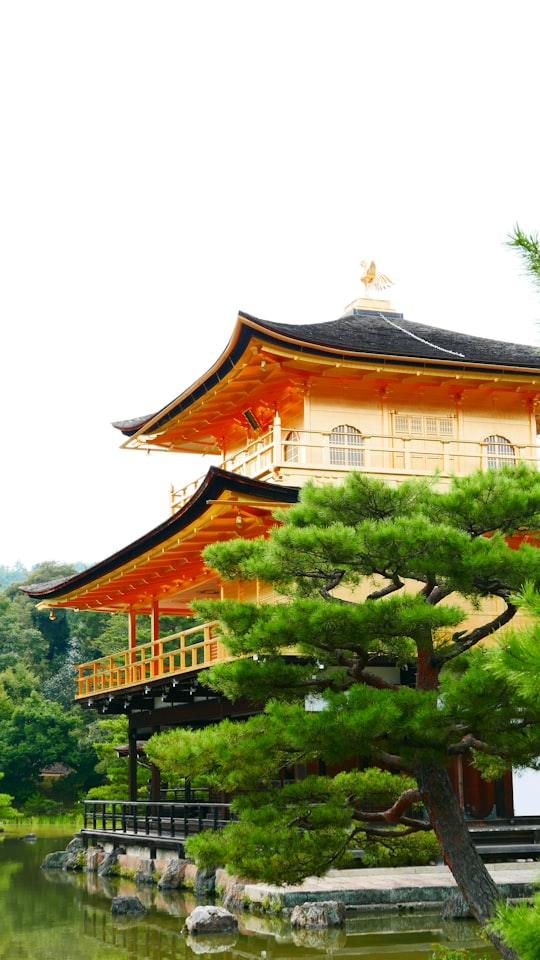 brown and white concrete building surrounded by green trees during daytime in Kinkaku-ji Japan