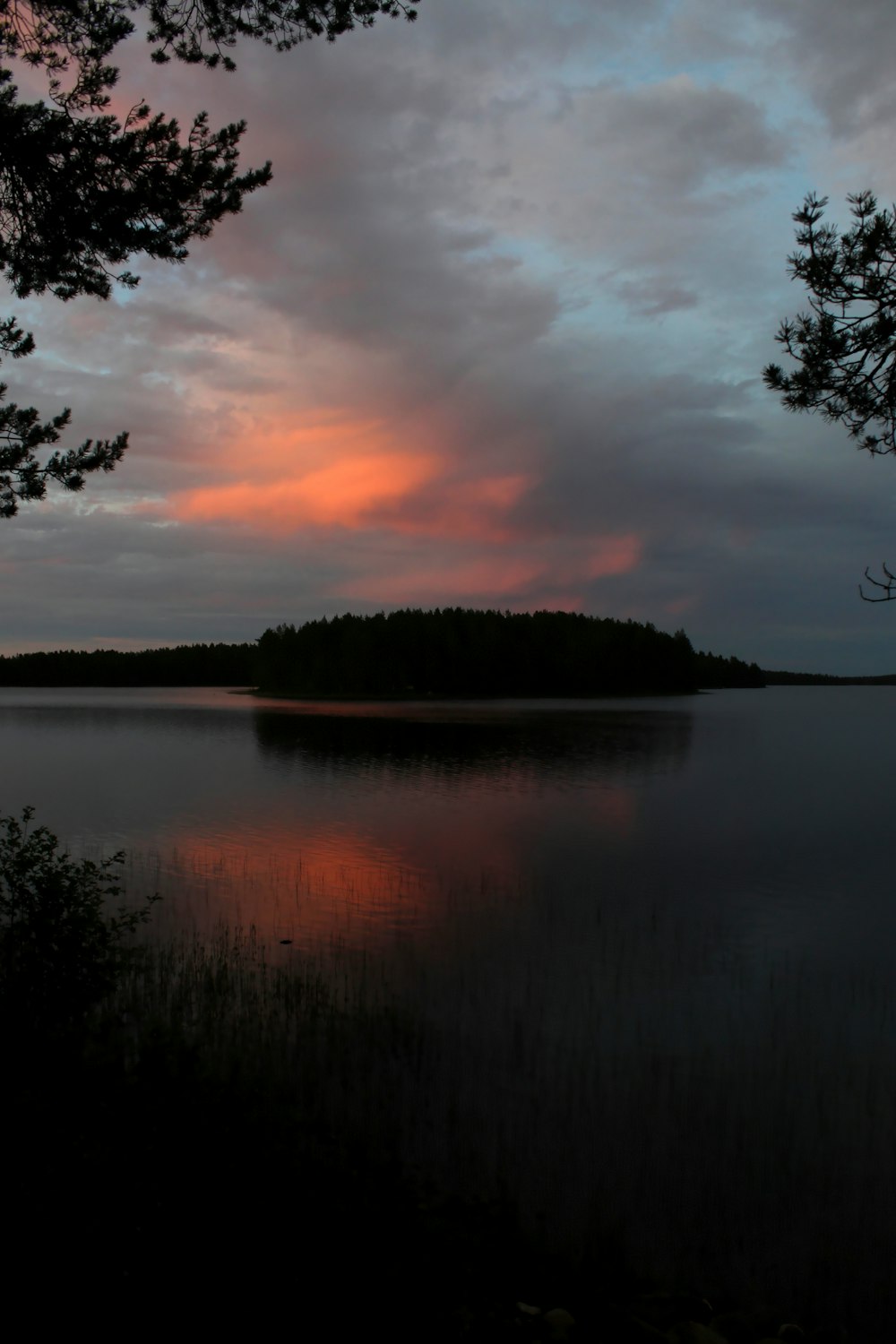 a sunset over a lake with a small island in the distance