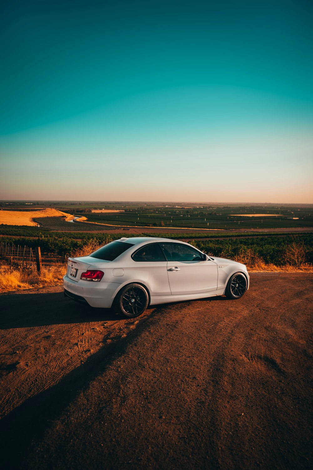 white sedan on brown dirt road during daytime