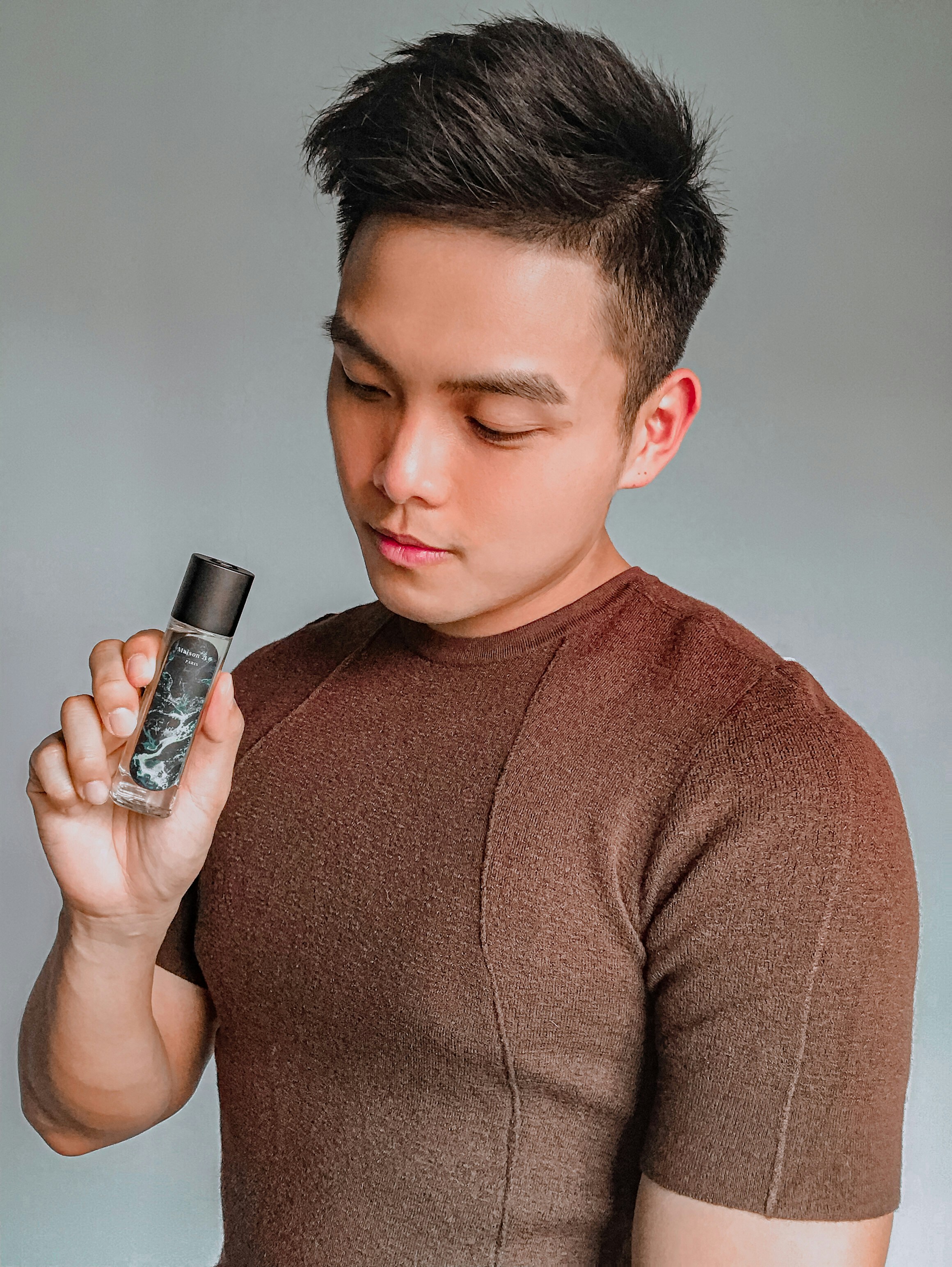 黒いボトルを持つ茶色のクルーネックセーターの少年