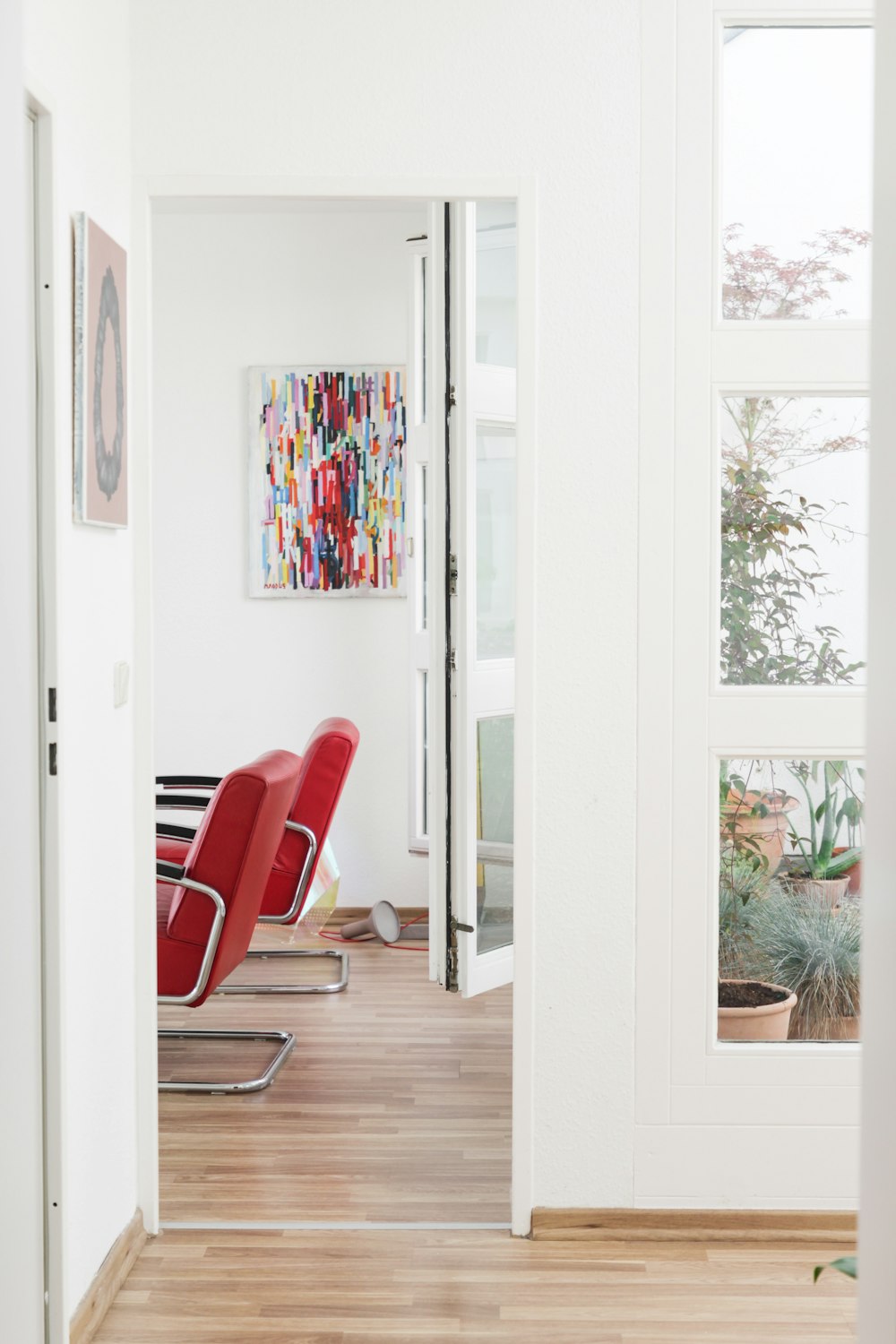 red and black armchair beside white wooden framed glass door