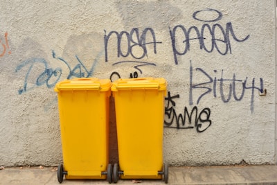 yellow trash bin beside white wall