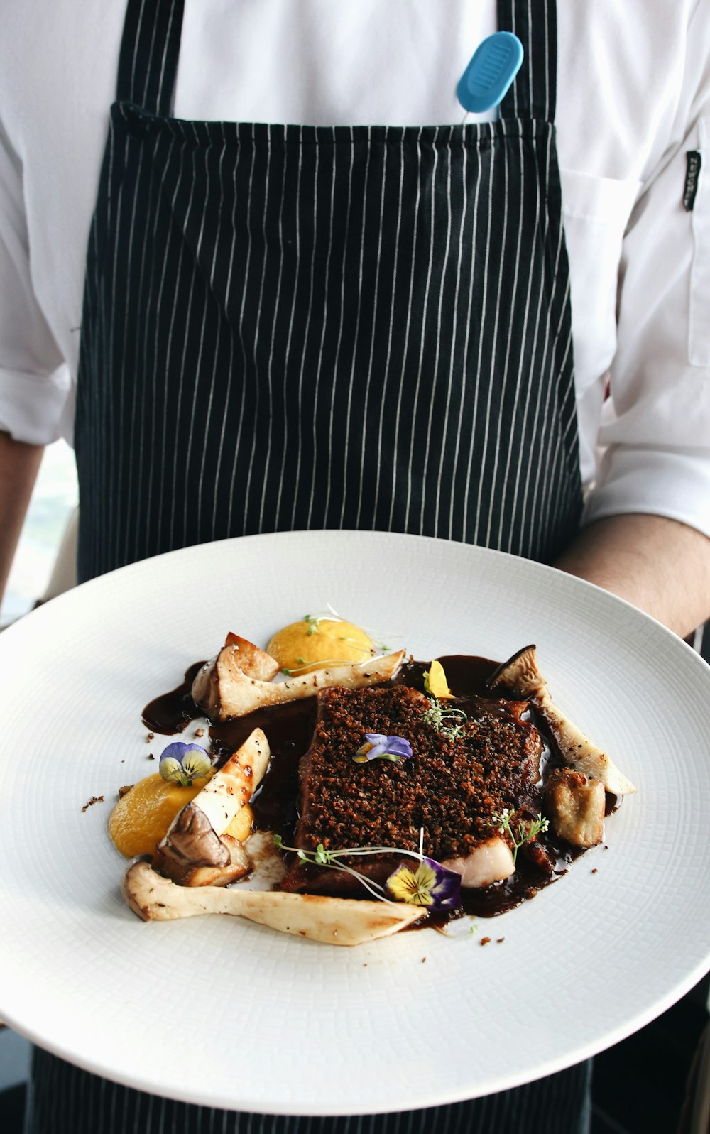 person in white dress shirt holding plate with food