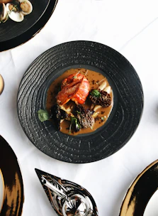 Close-up of a beautifully plated French fusion dish with vibrant colors on a black table.