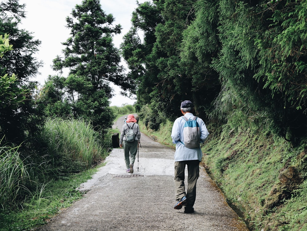 man in blue jacket walking with dog on road during daytime