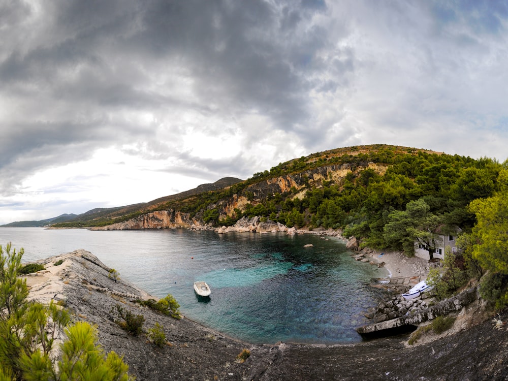 green and brown mountain beside body of water under cloudy sky during daytime