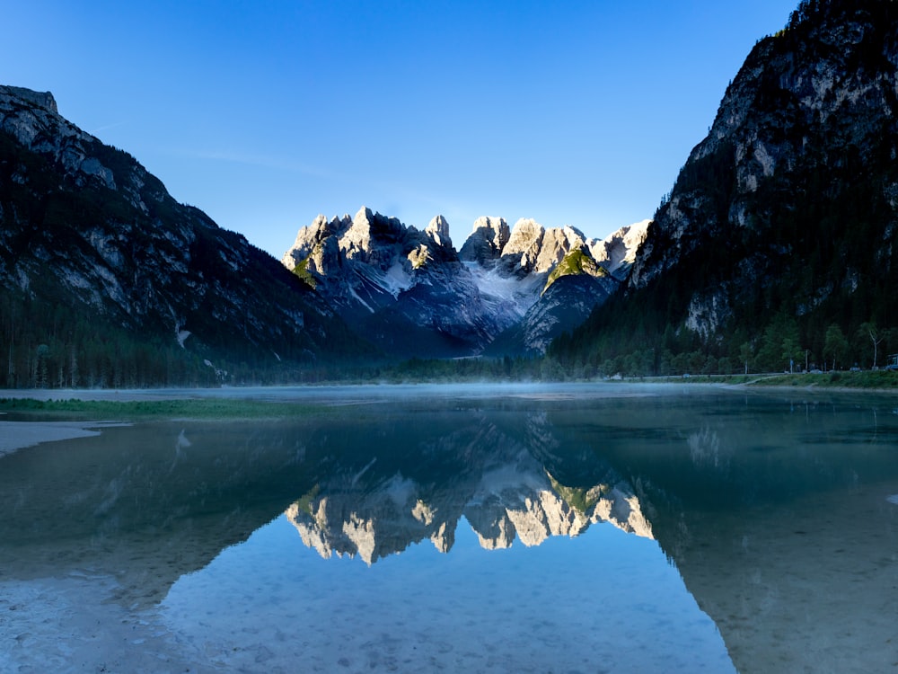 snow covered mountain near body of water during daytime