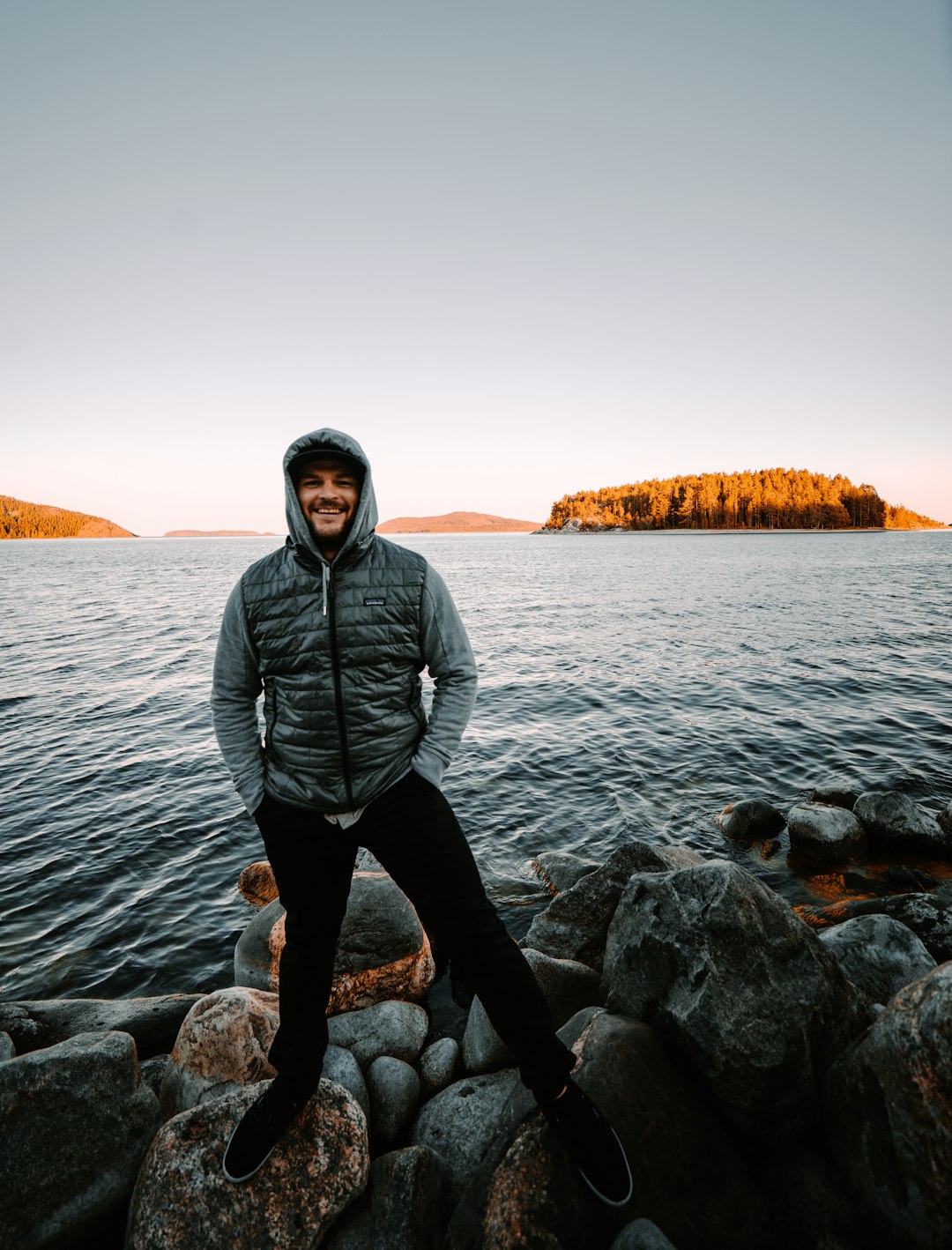 man in black jacket standing on rocky shore during daytime