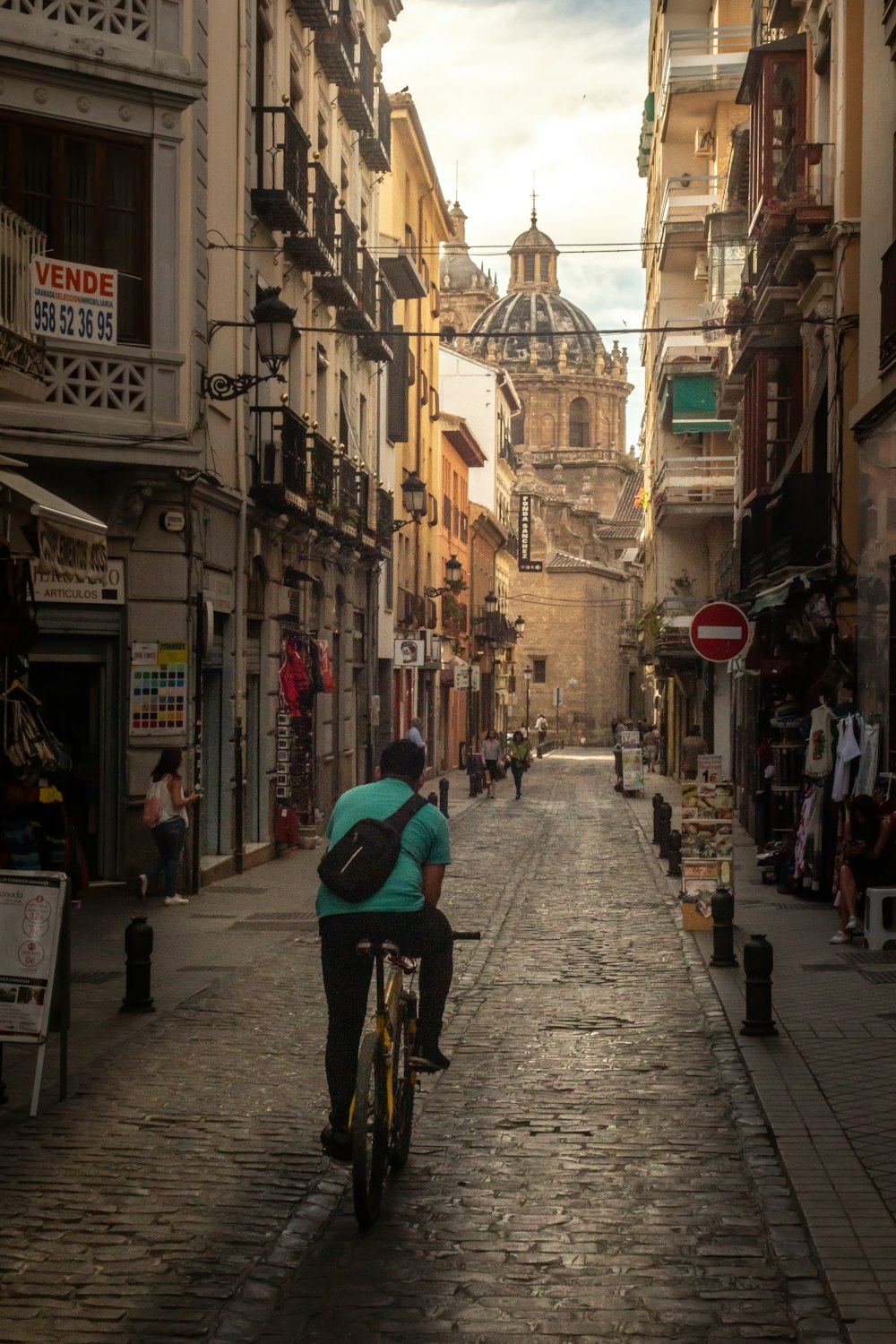 man in green jacket riding bicycle on street during daytime