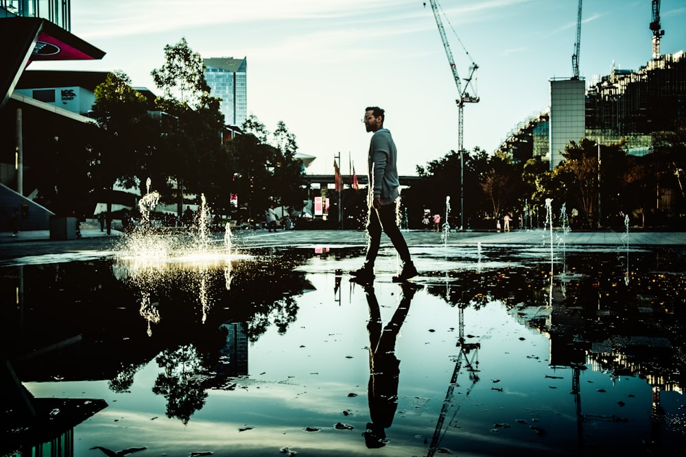 man in white shirt and black pants standing on water fountain during daytime