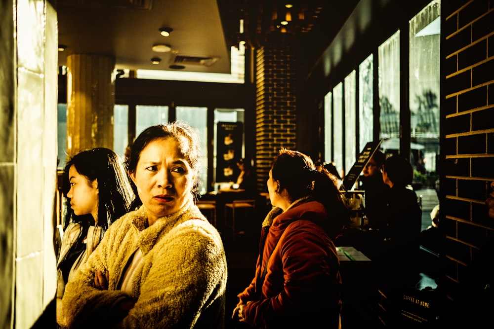 woman in white sweater sitting beside woman in brown coat