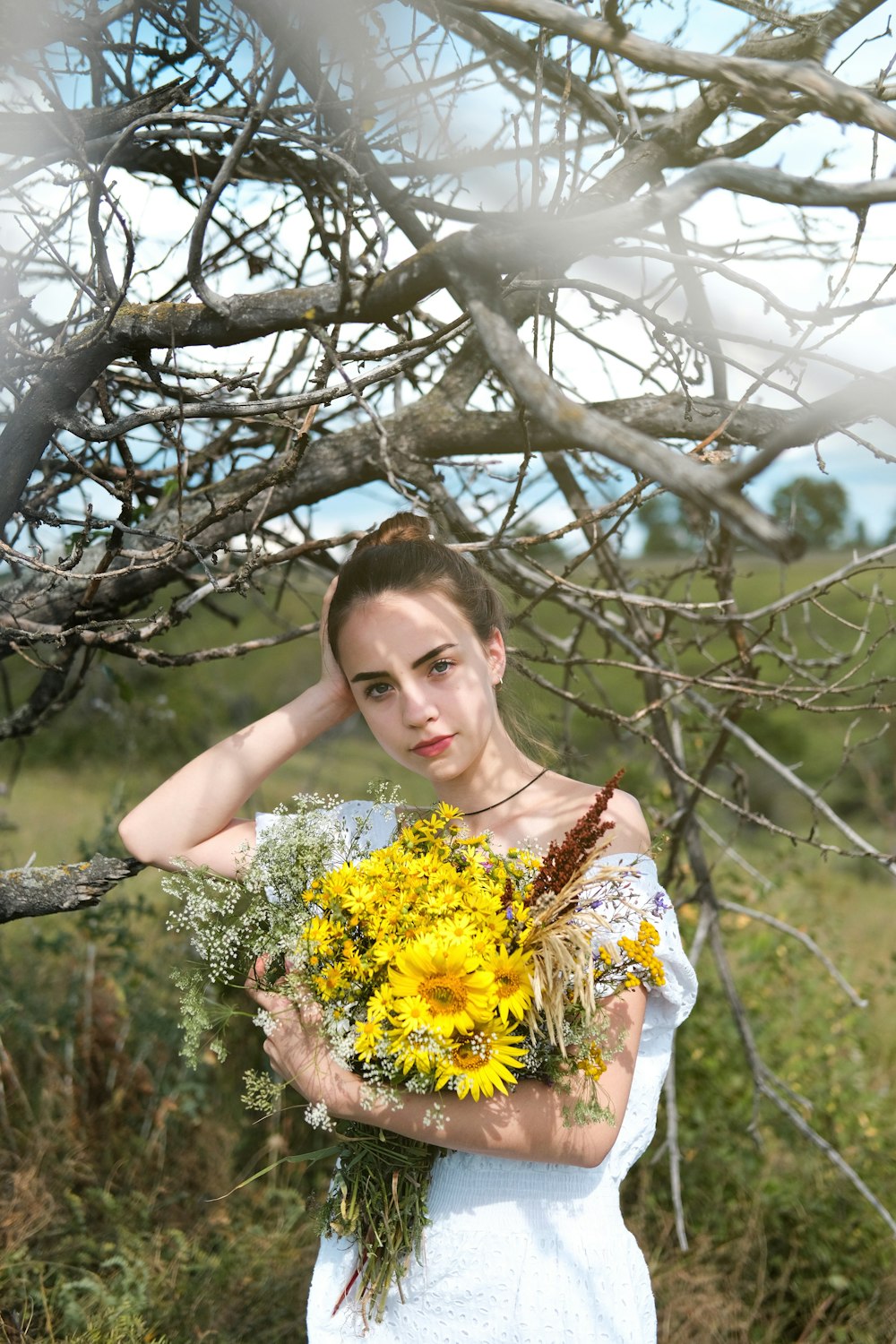 donna in abito floreale bianco e giallo che tiene fiori gialli