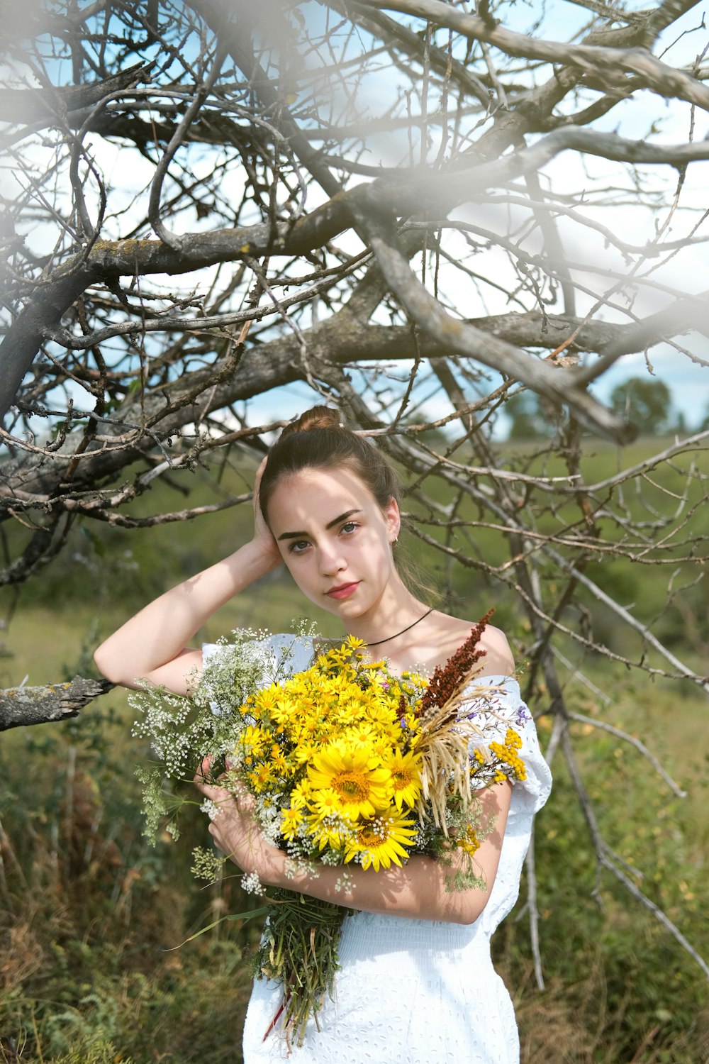 mulher no vestido floral branco e amarelo que segura as flores amarelas
