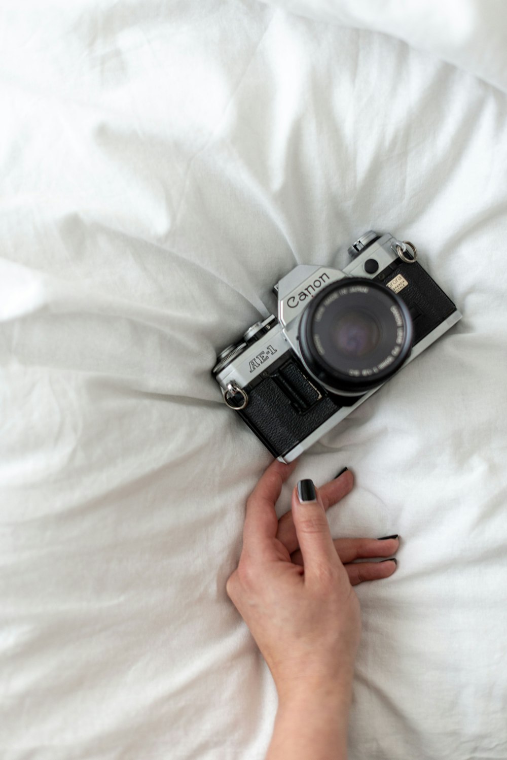 black and silver dslr camera on white textile