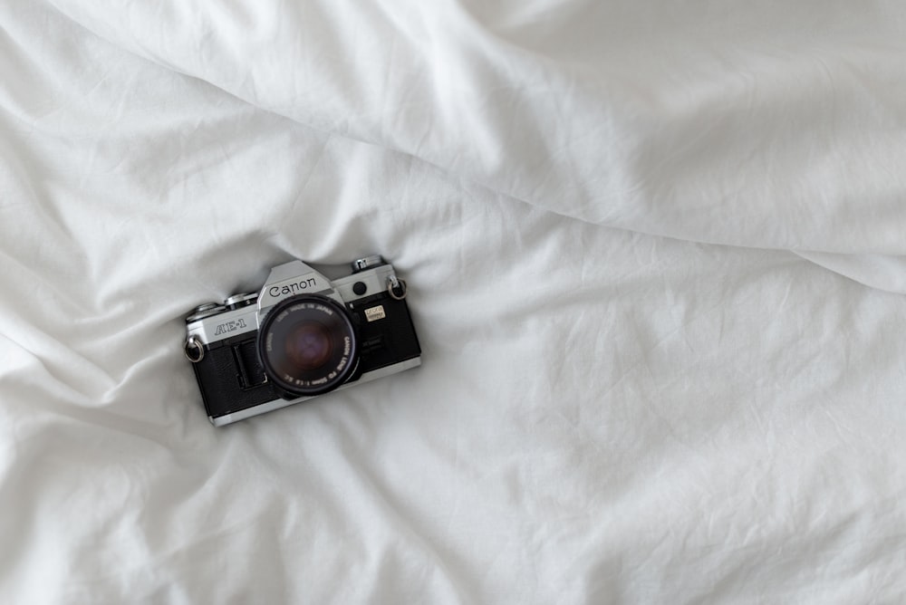 black and silver camera on white textile