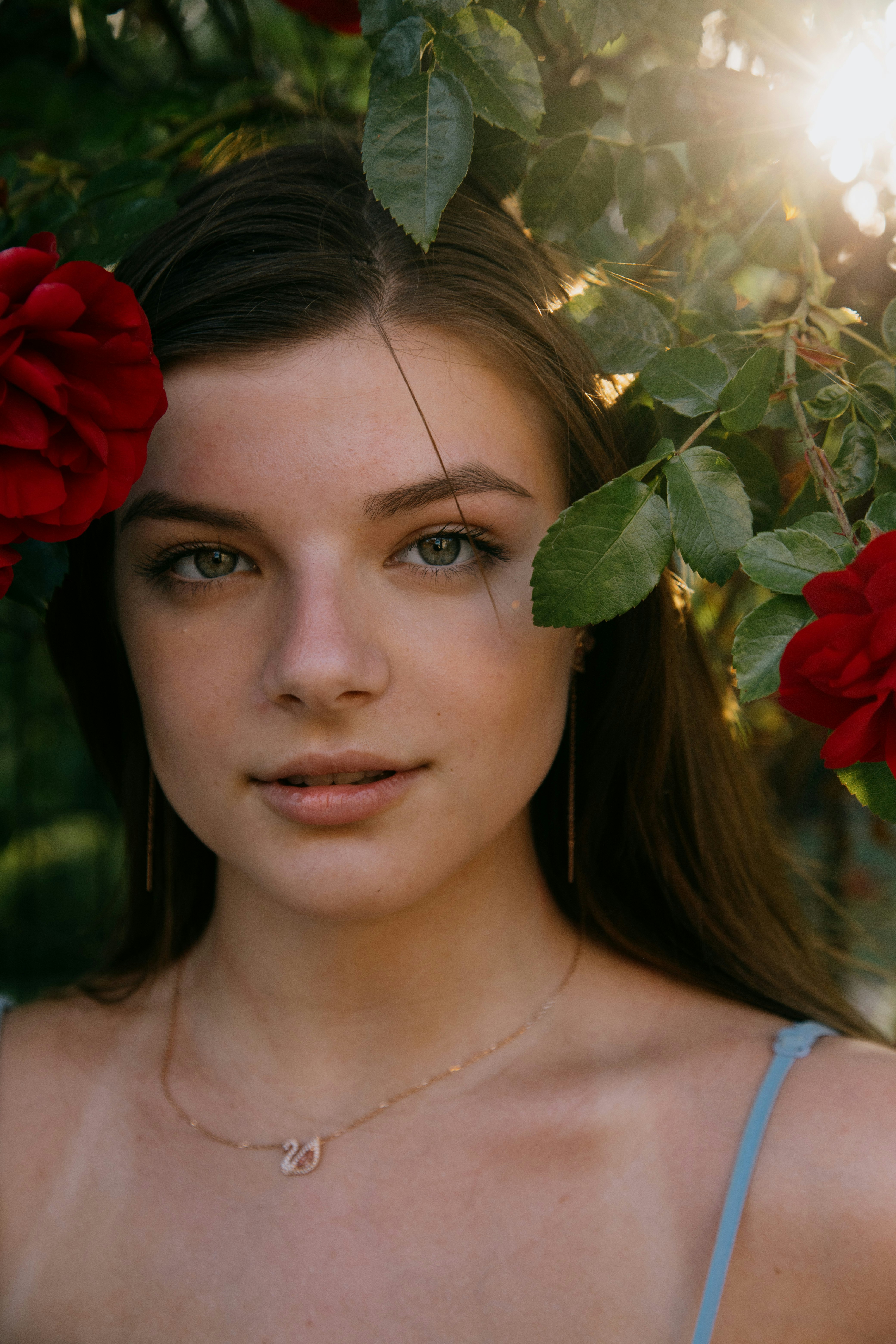 woman in blue tank top holding red rose