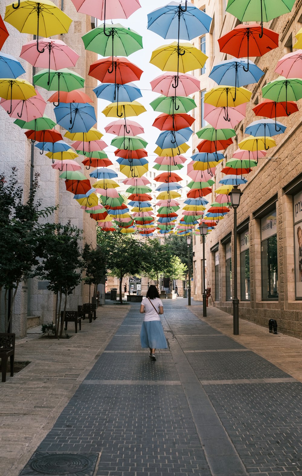 personas que caminan por la acera con paraguas multicolores en la calle durante el día