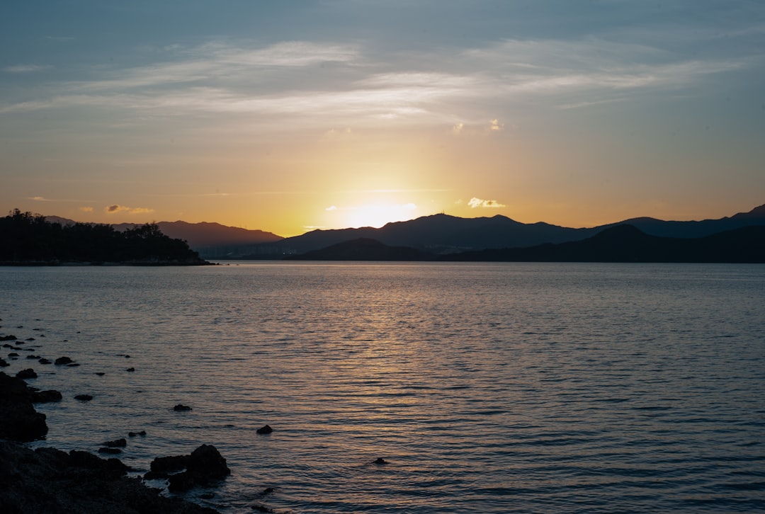 silhouette of mountain near body of water during sunset