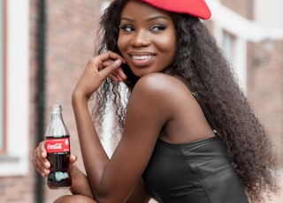 woman in black spaghetti strap dress holding coca cola bottle