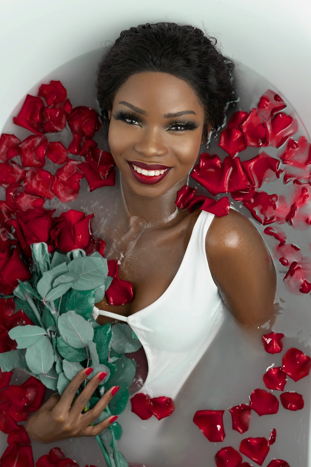 woman in white tank top holding red rose bouquet
