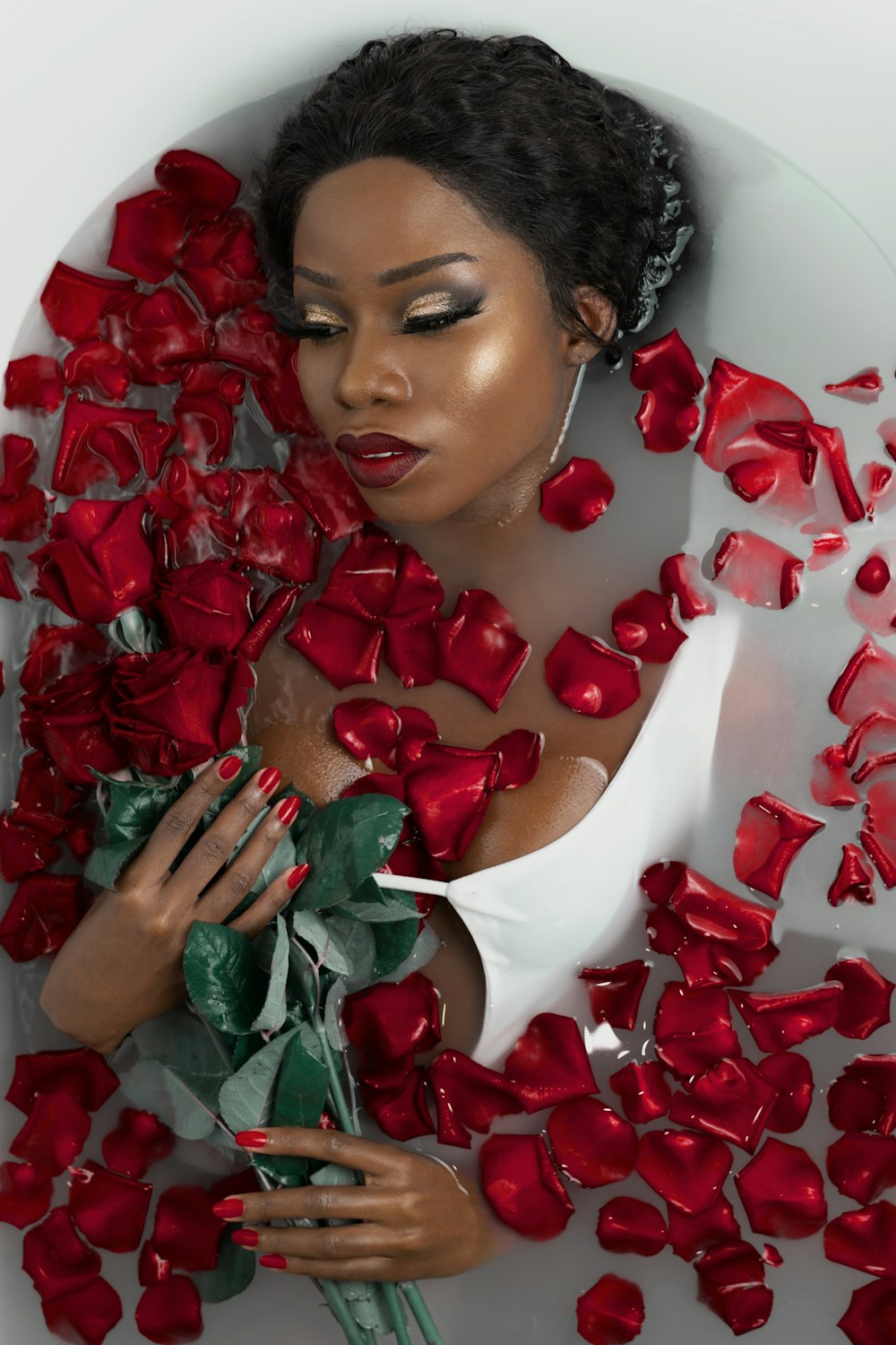赤いバラの花びらが顔に描かれた白いタートルネックシャツを着た女性