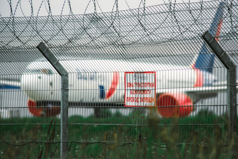 a plane behind a fence with a sign on it