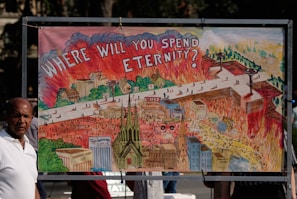 A detailed illustration depicts a scene with flames and smoke surrounding buildings, roads, and a church. The artwork features a large, bold text at the top questioning 'Where will you spend eternity?'. The imagery contrasts elements of chaos against more organized structures in a vibrant, symbolic representation.
