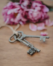An elegant concierge key set on a polished wooden table beside a small, tasteful bouquet of fresh flowers.