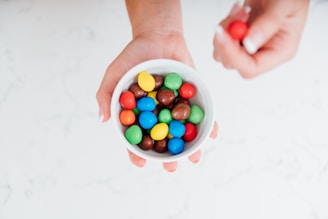 Hand holding a handful of mixed candies with various shapes and textures