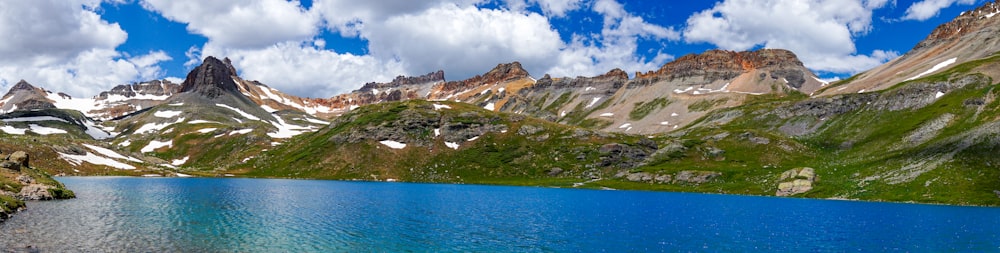 green and white mountains near blue sea under blue and white cloudy sky during daytime