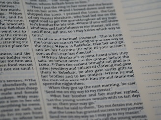 A close-up view of a page from a book with printed text in English. The passage appears to be from a religious or historical context, focusing on a dialogue involving Laban, Bethuel, and Abraham’s servant. The text is arranged in paragraphs with verse numbers in bold. Blank lined sections are visible on the opposite page.