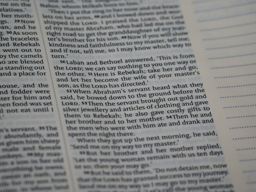 A close-up view of a page from a book with printed text in English. The passage appears to be from a religious or historical context, focusing on a dialogue involving Laban, Bethuel, and Abraham’s servant. The text is arranged in paragraphs with verse numbers in bold. Blank lined sections are visible on the opposite page.