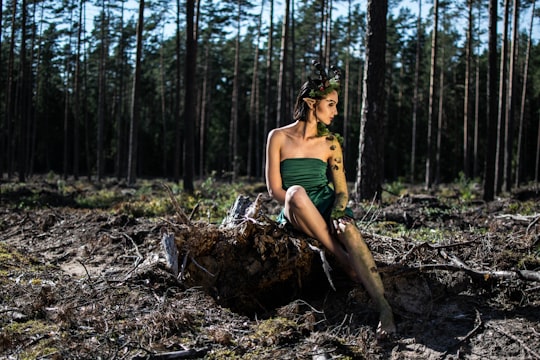woman in green spaghetti strap dress sitting on brown tree log during daytime in Kaunas Lithuania