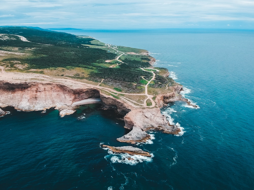 green grass covered mountain beside blue sea during daytime