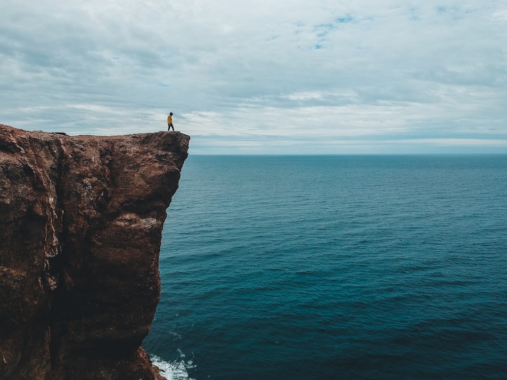 person standing on rock formation near sea during daytime